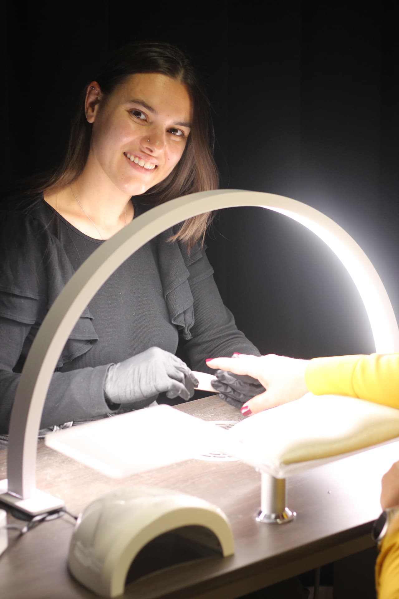Nagelstyliste van Nistre glimlachend aan haar werktafel